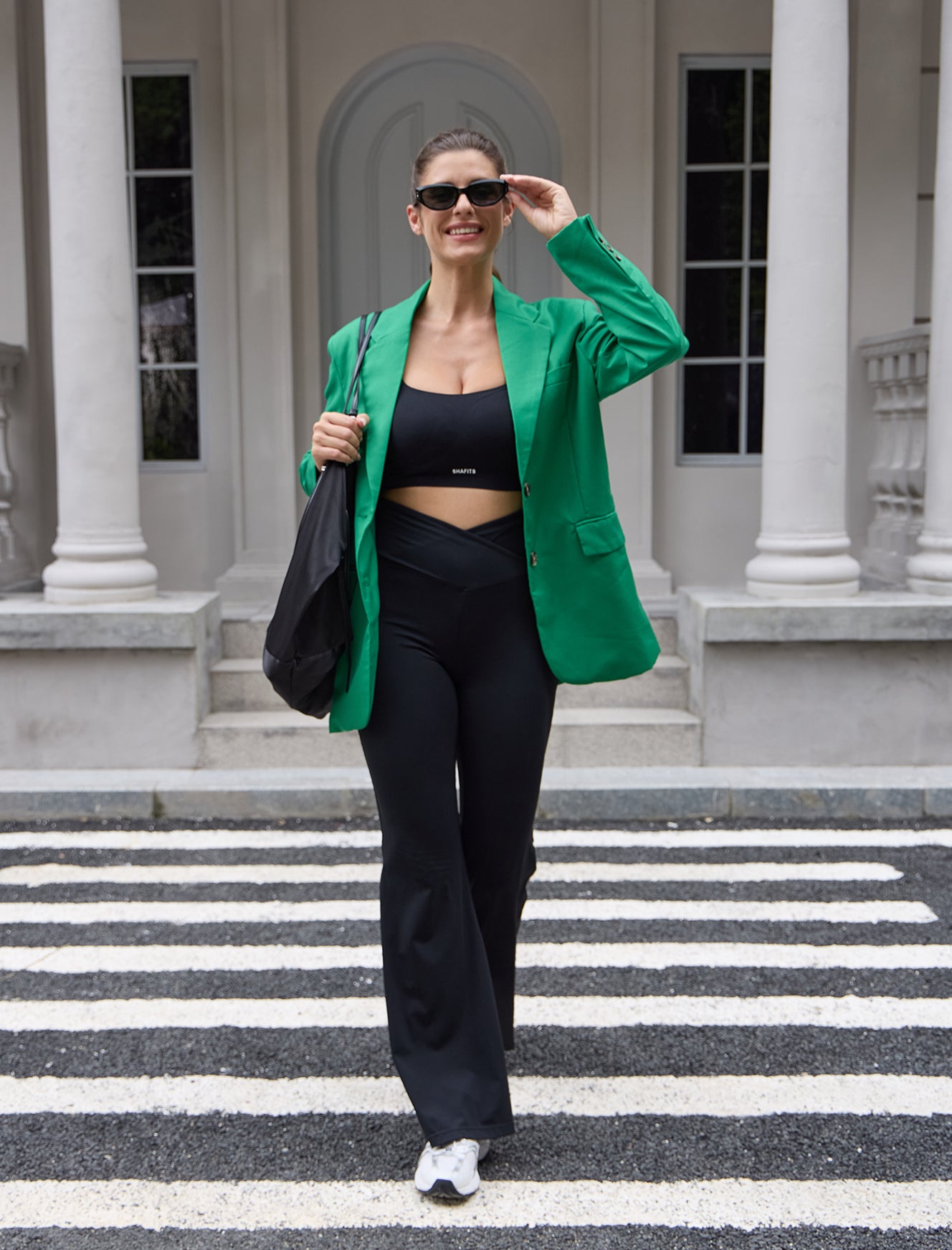 Wearing a black sports bra and black flared yoga leggings, forming a sportswear ensemble, walking on the street